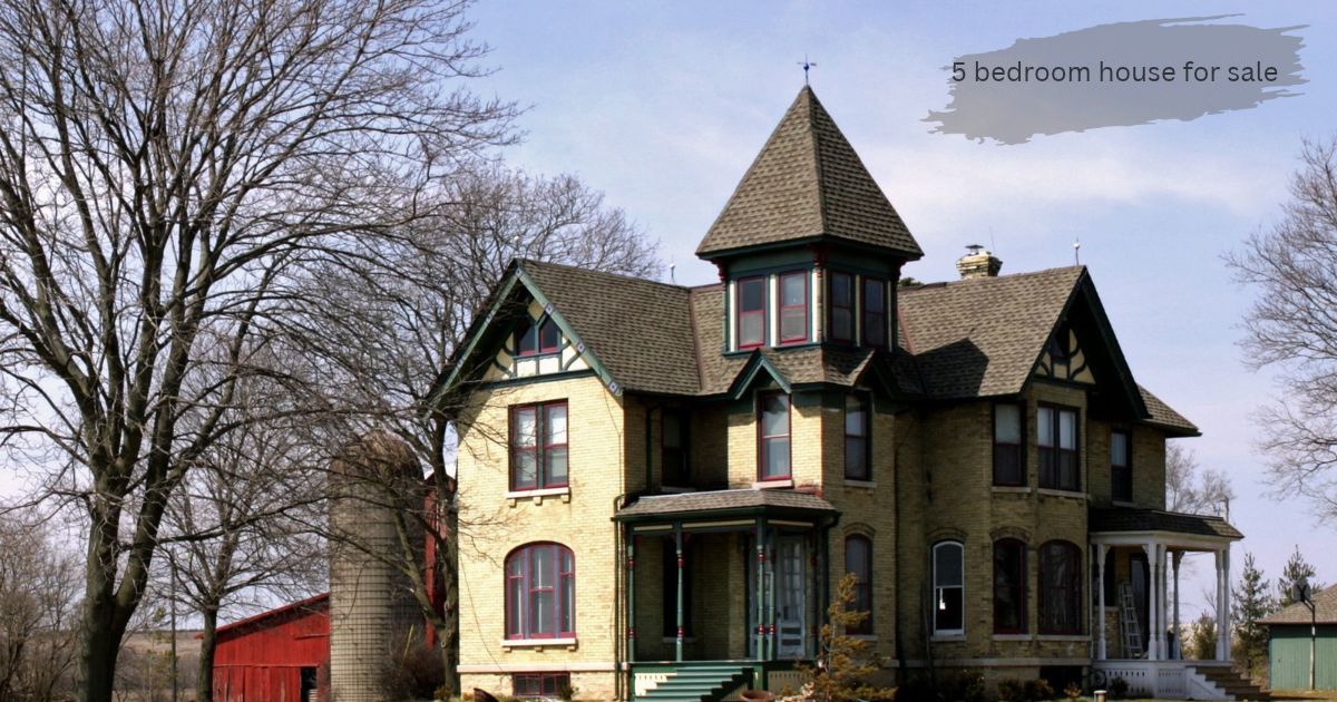 A historic, multi-story brick farm home next to a red barn with a tall silo and large bare trees in the front yard.’5 bedroom house for sale’