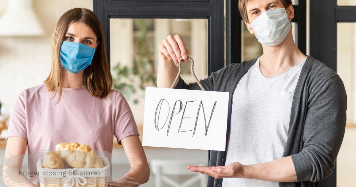 Two masked shop workers holding an open sign and fresh bread, showing stores that stay open during the Kroger closures." kroger closing 60 stores "
