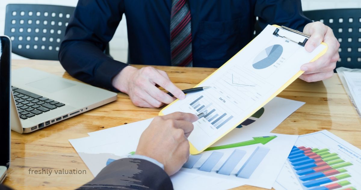 freshly valuation report with pie and bar charts on a yellow clipboard as two professionals review the numbers at a wooden table