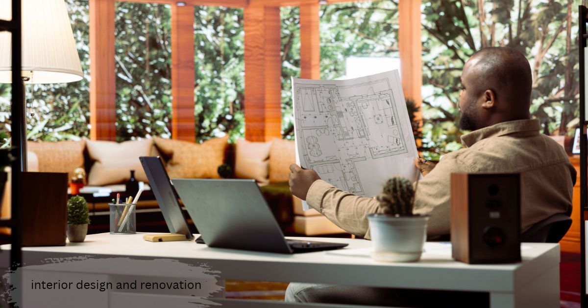 Man at a desk studying a home floor plan beside a laptop, planning an interior design and renovation project
