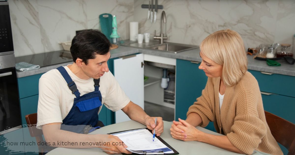 Contractor in blue overalls pointing how much does a kitchen renovation cost at a quote on a clipboard while a homeowner listens at a table in a teal and marble kitchen, discussing kitchen renovation pricing
