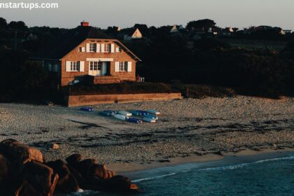 Sandy shoreline at Couture Beach Lakeshore featuring historic brick cottage beached boats rocky coast and lakeshore community at sunset