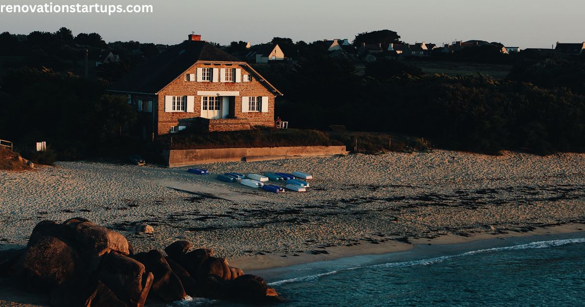 Sandy shoreline at Couture Beach Lakeshore featuring historic brick cottage beached boats rocky coast and lakeshore community at sunset