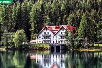 Forest Hill style white home with red roof nestled among pine trees by a lake