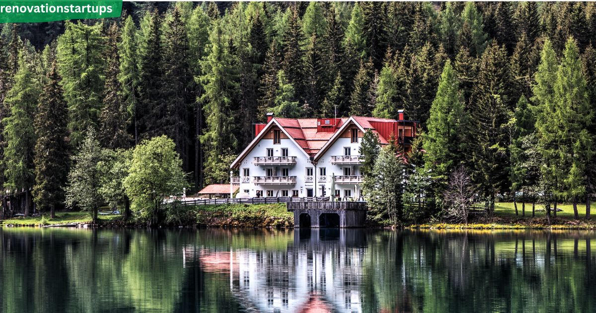 Forest Hill style white home with red roof nestled among pine trees by a lake