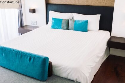 A neatly made queen size bed showcasing standard bed sizes canada dimensions in a modern bedroom with white linens, turquoise pillows, and dark wood nightstands.