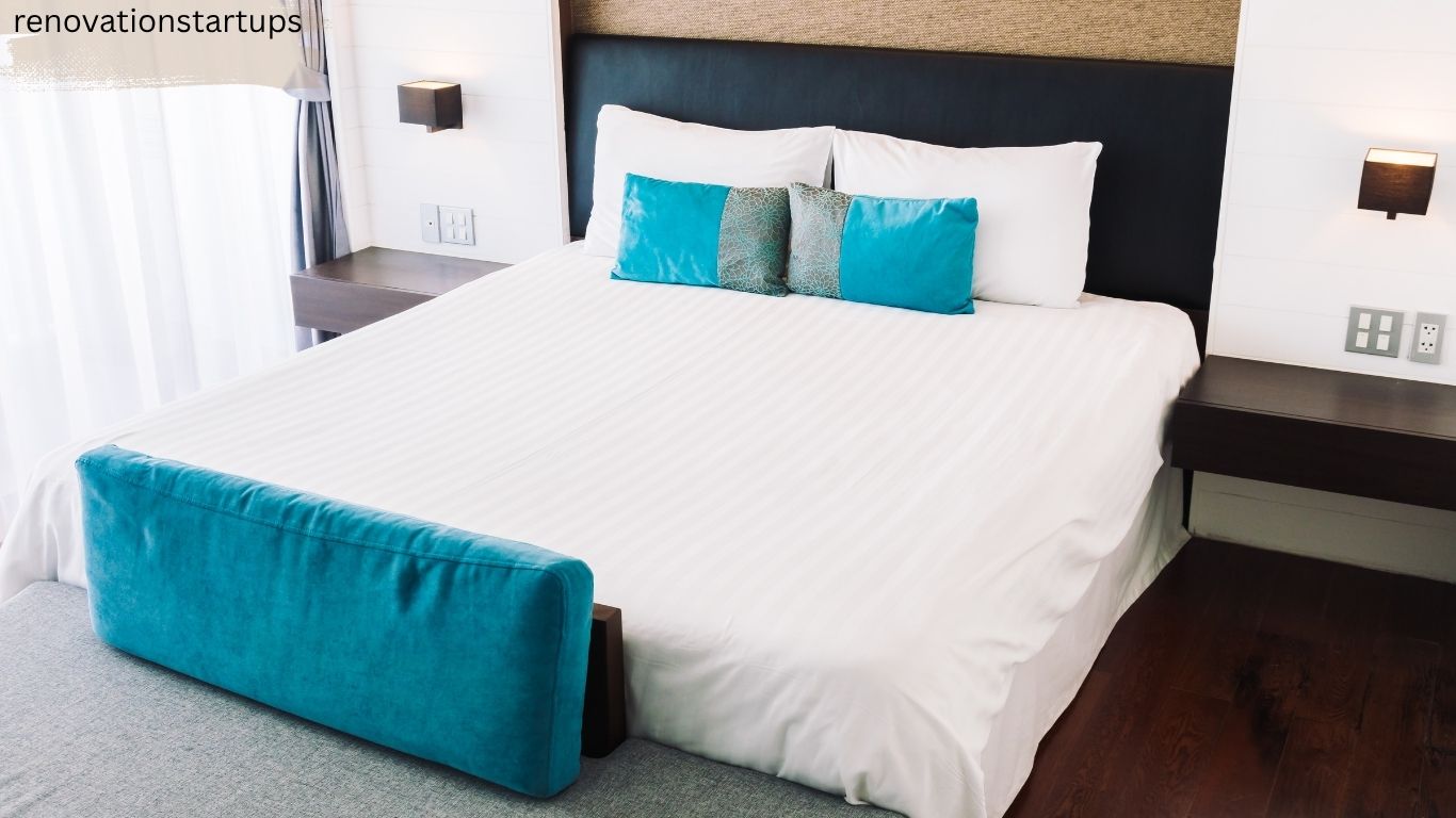 A neatly made queen size bed showcasing standard bed sizes canada dimensions in a modern bedroom with white linens, turquoise pillows, and dark wood nightstands.