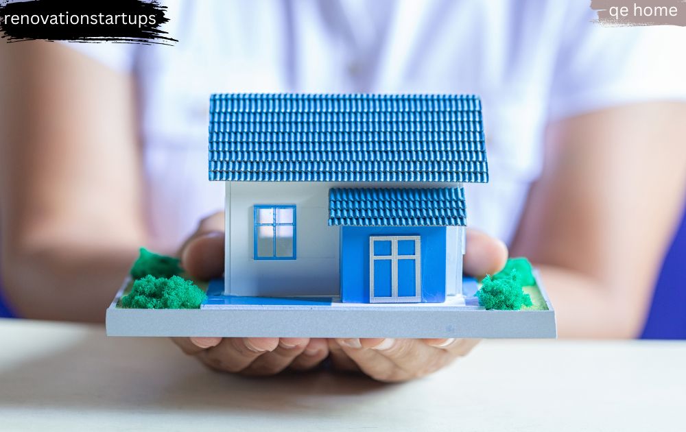Hands holding a blue miniature house model representing QE Home Canada's trusted family-owned brand