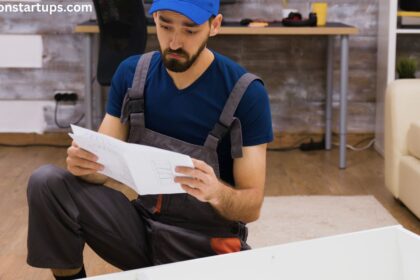 Contractor in overalls reviewing blueprint sketches to estimate basement renovation cost