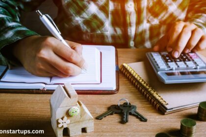 Person calculating house renovation costs with calculator, notebook, house model, keys, and coins on desk.