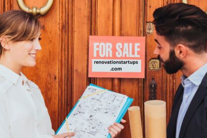 Real estate agent showing house blueprints to buyer beside a For Sale sign on a wooden front door in St. Catharines.