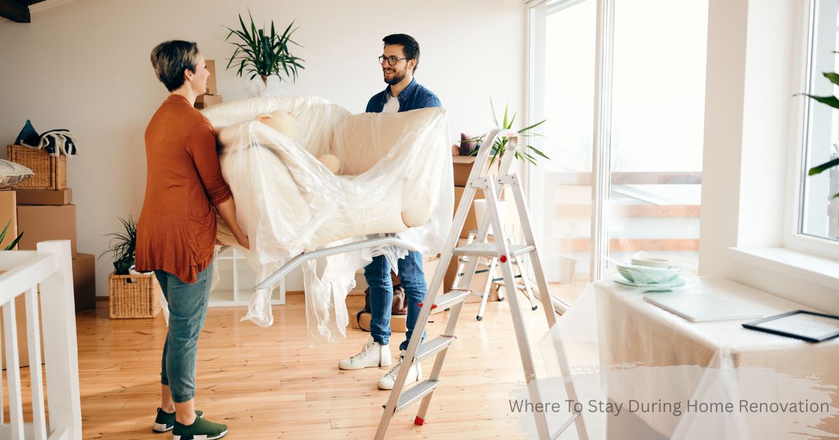 Couple wrapping furniture in plastic while packing up their home during a renovation, with moving boxes and a ladder in the background — where to stay during home renovation.