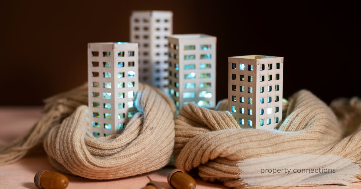 Miniature illuminated apartment buildings wrapped in a cozy knit scarf, representing property connections for a warm, secure home