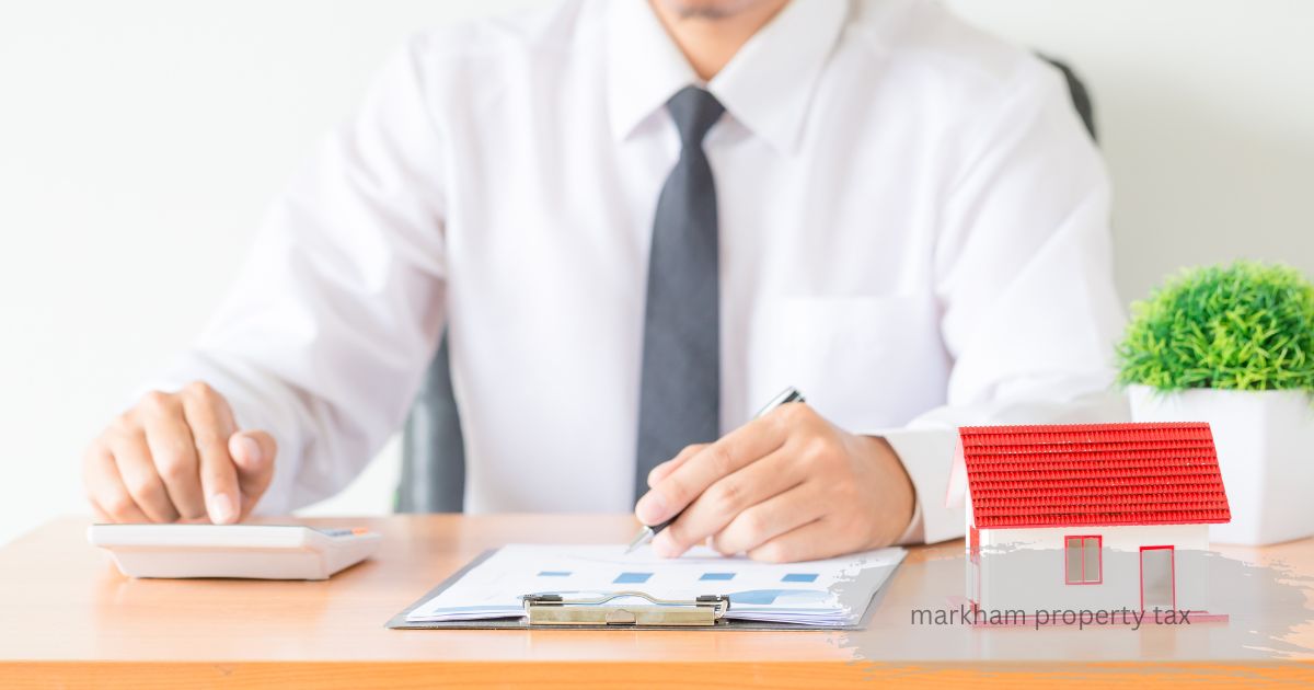 Man in white shirt calculating Markham property tax with calculator, documents, and house model on desk