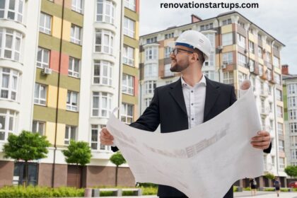 Man in a hard hat and suit reviewing property blueprints outside a row of multi-storey apartment buildings, representing Winnipeg property assessment and building valuation.