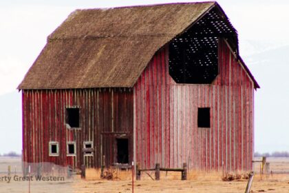 Weathered red barn with a partially collapsed roof standing in an open field Lost Property Great Western