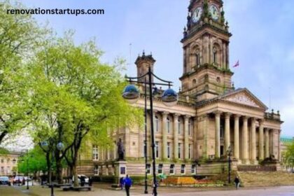 Bolton Town Hall clock tower and columned portico with tree-lined square in spring