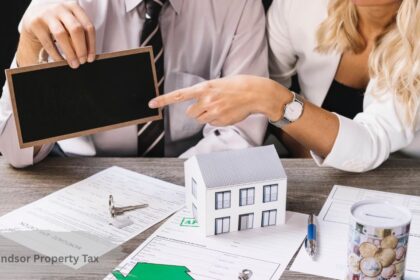 Couple reviewing a mortgage application and pointing to a small house model, illustrating the City of Windsor property tax homeowner guide.