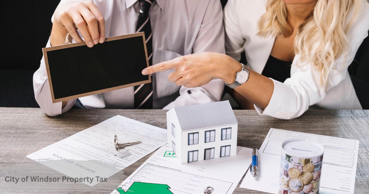 Couple reviewing a mortgage application and pointing to a small house model, illustrating the City of Windsor property tax homeowner guide.