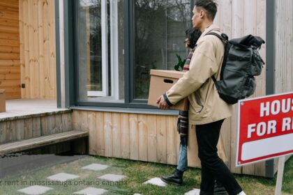 Red house for rent sign in front of people touring potential houses for rent in Mississauga Ontario Canada