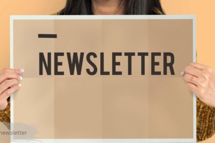 Person holding a sign that reads "Newsletter" against an orange background — current newsletter
