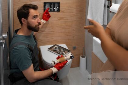 Toronto bathroom renovation cost: plumber repairing toilet cistern while homeowner looks on