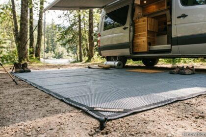 Durable grey markiseteppe awning carpet staked to campsite ground beneath extended camper van awning in forest environment.