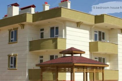 Exterior view of a modern multi-story residential building with light-colored siding and brown window frames. '5 bedroom house for sale'