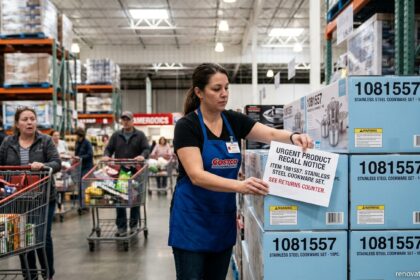 Costco employee placing an urgent product recall notice on item 1081557 boxes inside a warehouse store