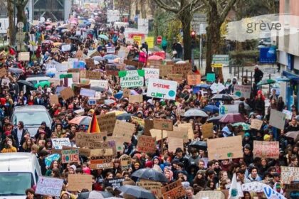 Grève march with crowds of protesters holding signs demanding climate action and workers' rights