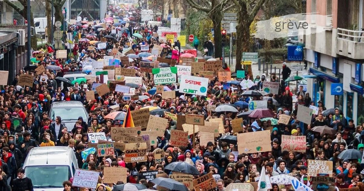 Grève march with crowds of protesters holding signs demanding climate action and workers' rights