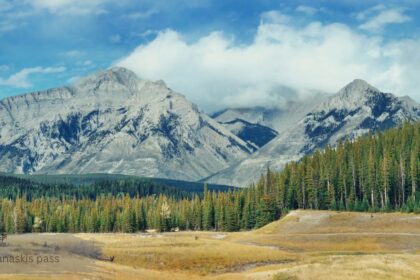 Kananaskis pass mountain range with snow capped peaks and highway through forest