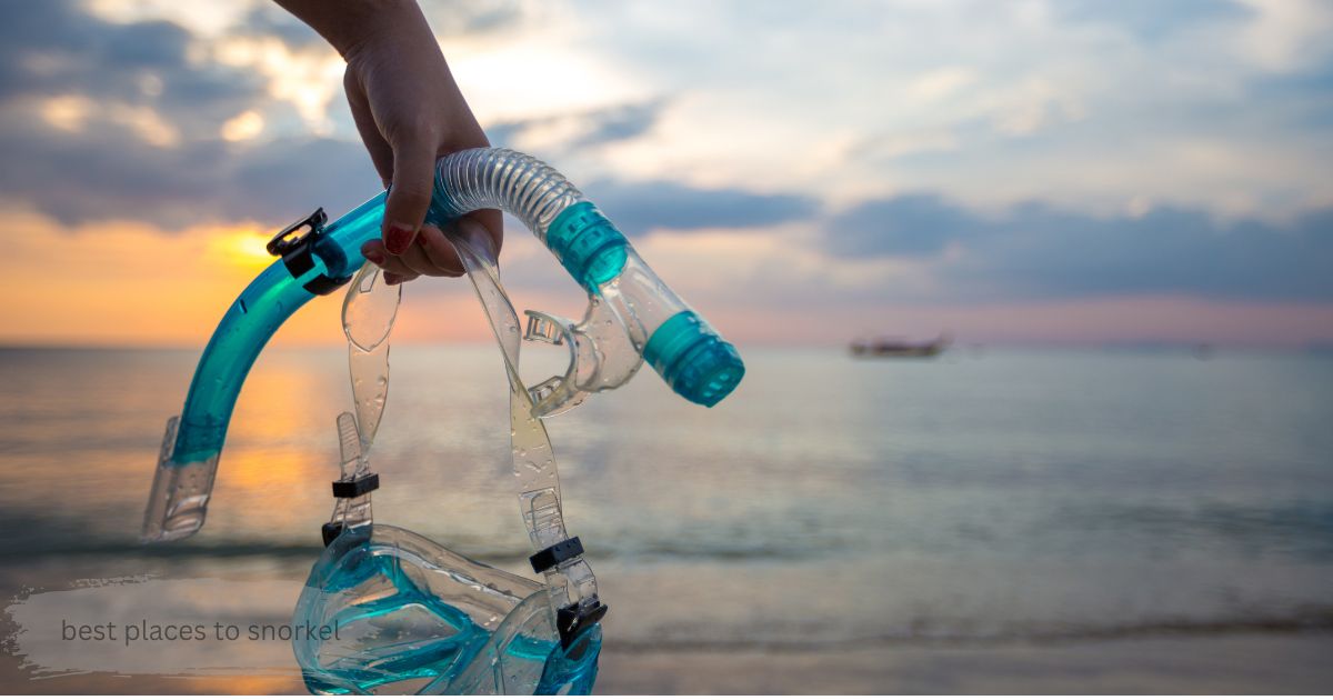 Snorkel mask and tube held up at sunset, symbolizing one of the best places to snorkel for a beach getaway
