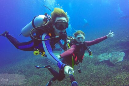 Two divers exploring a coral reef underwater with scuba gear during a snorkeling and diving trip