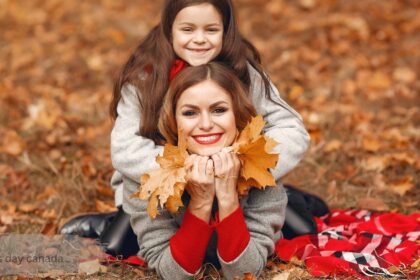 mothers day canada - mother and daughter in red winter outfits smiling on a snowy bridge