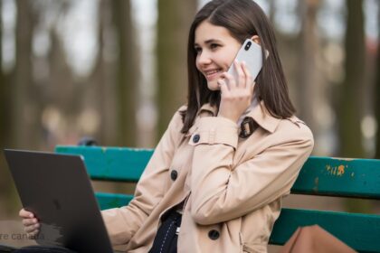 Woman using laptop and talking on phone outdoors while comparing Hotwire Canada travel deals