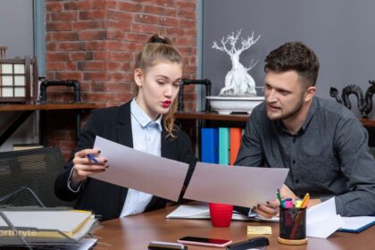 Coworkers reviewing torn document together at office desk, forthryte team discussion.