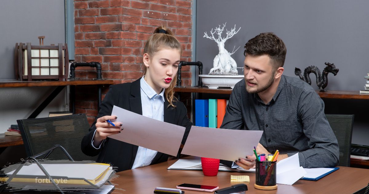 Coworkers reviewing torn document together at office desk, forthryte team discussion.