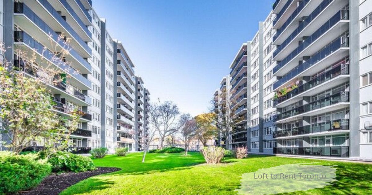Two high rise apartment buildings with balconies facing a green courtyard lawn under a blue sky, a loft to rent in Toronto.