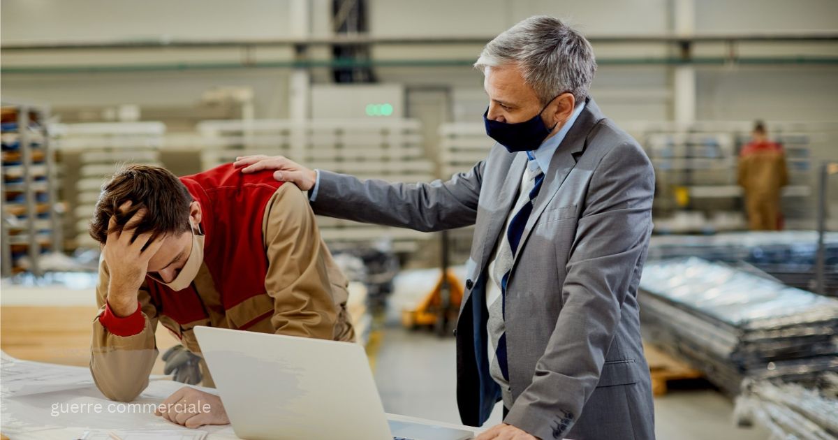 Manager comforting a stressed worker at a laptop in a warehouse, guerre commerciale